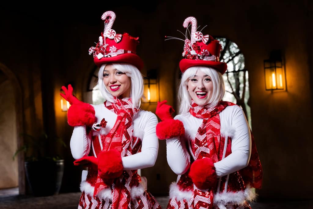 Two peppermint-striped candy-cane performers pose under an archway
